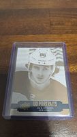 Photo shows a Jack Hughes rookie hockey card from the UD Portraits series, depicting him in his New Jersey Devils gear, encased in a clear plastic card holder to protect the card.