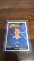 Photo of a Joseph Woll rookie hockey card in a protective sleeve showing colorful neon background and player in blue Maple Leafs jersey.