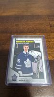 Photo of Joseph Woll rookie hockey card featuring him in goalie gear with Toronto Maple Leafs jersey, encased in plastic sleeve.