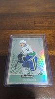 Photo of Quinn Hughes rookie hockey card in protective plastic holder on wooden surface.