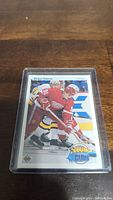 Young Guns hockey card featuring Sergei Fedorov in Detroit Red Wings uniform encased in plastic protective sleeve on wooden table.