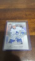 Photo of a William Nylander rookie hockey card in a protective sleeve on a wooden surface.