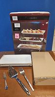 Photo showing boxed 3 tier server and included serving utensils on table