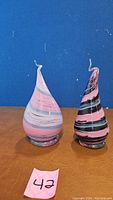 Two blown glass decorative sculptures front view on a brown surface with blue background, labeled with pink tag 42.