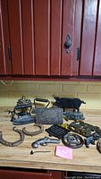 Overview of all cast iron items on wooden countertop beneath wooden cabinets, showing assorted trivets, door stops, a buffalo figure, horseshoes, and other cast iron pieces.