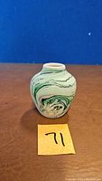Front view of small Nemauji pottery bud vase showing the green and cream marble pattern and narrow neck opening.