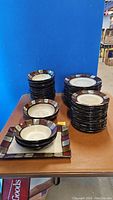 Photo showing stacks of different plates and bowls with geometric patterned border in various earth tones.