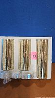 Three mercury glass light vases held in foam packaging showing their cylindrical shape and metallic finish.