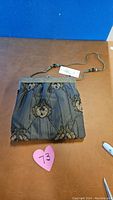 Full front view of vintage India beaded purse on table with heart-shaped pink tag labeled '73'