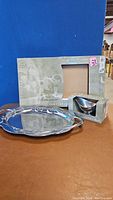 Large oval tray with scroll edge and polished gravy boat in box, both displayed on a table