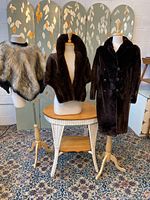 Full view of three vintage fur jackets on mannequins: faux fur poncho on left, mink stole center, sheared beaver coat right.