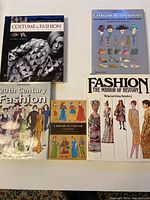 Five fashion and costume history books arranged on a flat surface showing titles and covers