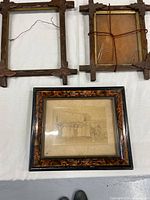 Three vintage wooden picture frames displayed on table, showing condition and details.