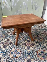 View of the top and side of a rectangular wooden coffee table showing its carved edge and wooden surface with stains.