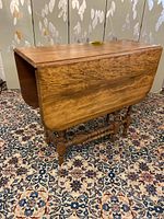 Front side view of the stained wood gate leg table with sides up showing table length and leg design.