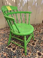 Side angle showing green painted wooden barrel chair with spindle backrest, round seat, and turned spindle legs. Paint shows age wear, chip marks present.