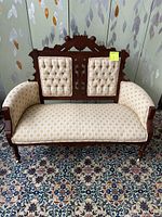 Front view of the settee showing detailed Eastlake style solid wood carved back, tufted upholstery panels and overall state.