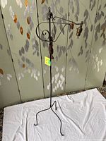 Full view of the black wrought iron floor lamp showing its structure, 3-legged base, and adjustable arm.