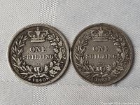 Pair of silver one shilling coins dated 1839 and 1840, reverse side showing denomination and wreath detail.