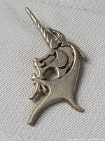 Front view of unicorn-shaped sterling silver pendant resting on fabric background showing detailed horn, head, and mane pattern.