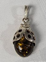 Front view of the ladybug pendant showing amber stone and silver wings with detailed cutouts.