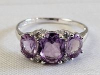 Front view of ring showing three oval amethyst stones and accent stones