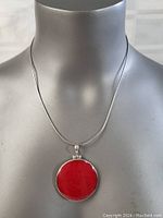Frontal view of necklace on mannequin bust showing the red coral circular pendant and sterling silver chain.
