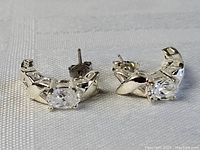Front angle of pair of sterling silver stud earrings with clear oval stones visible in setting.