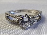 Front view of ring showing round center stone and split shank with pave-set accent stones.