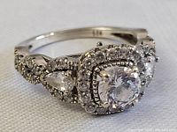 Front right 45° angle showing center stone, square halo and right pear-shaped side stone