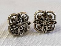 Close-up of vintage sterling silver earrings with marquisette floral design and patina on white background