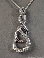 Close-up of the sterling silver spiral pendant showing the encrusted small clear stones and shiny silver finish.