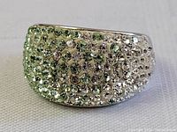 Close-up photo of sterling silver wide band ring densely encrusted with small clear crystals on the outer surface.