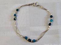 Full view of the sterling silver and blue stone bead bracelet against fabric background.