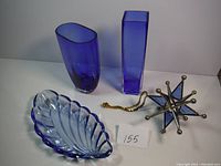 Photo showing two purple glass vases, blue-purple leaf-shaped glass dish, and mid-century modern starburst pendant light fixture with chain.