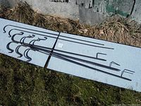 Five metal shepherd's hooks laid out on the ground, showing full length and curved hook tops