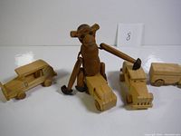 Wooden monkey figurine sitting on wooden toy cars, front view showing all items