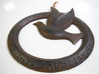 Close-up of dark brown cast iron decor piece showing the bird and inscription.