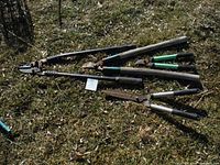 Four garden clippers and loppers arranged on grass showing handles and blades