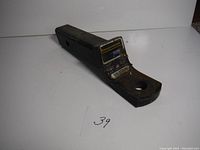 Black metal Reese trailer hitch with label visible and some surface rust, shown standing upright.