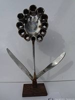 Full view of the handmade metal flower sculpture including base and knives as leaves