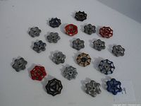 Lot of 19 vintage metal valve handles in assorted colors and designs displayed on a white background.