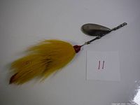 Full length view of XL bucktail spinner showing yellow fur tail, wire shaft, and metal spinner blade with swivel attachment.