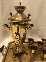Photo showing the brass samovar coffee pot, the decorative tray with detailed floral engraving, and some of the mini cups.