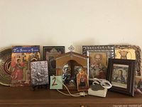 Photo showing the entire lot including the book, several framed religious icons in various sizes, and the wooden lighted altar box with power cord.