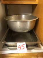 Large metal bowl sitting atop two large rectangular metal trays