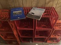Two hardcover John F. Kennedy books resting on a stack of orange plastic milk crates.