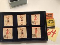 Overview of 8 match packs in blue display tray, showing six match packs with illustrated pin-up girls.
