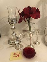 Photo of all four items including three silver candle stands and a red glass dish.