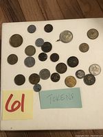 Overview of 24 assorted tokens including metal and plastic varieties arranged on a white surface.